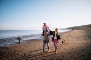Family walking along a beach with their dog